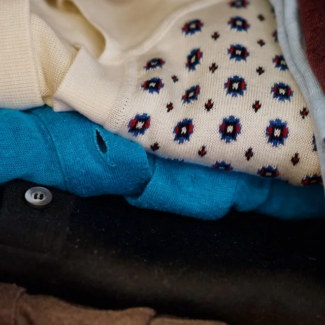 Photograph of folded knits in turquoise, navy and cream.