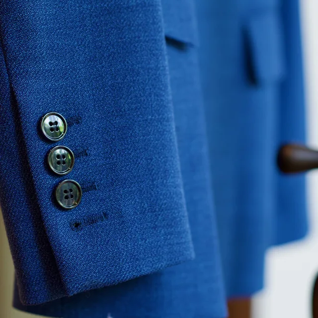 Photograph of a cobalt wool sleeve with three buttons.