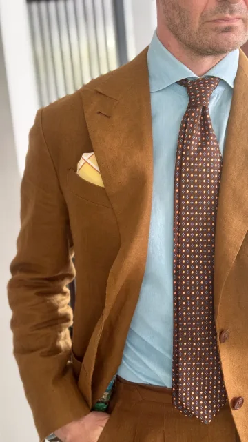 Detail of John Philip Green’s brown jacket, blue shirt, patterned tie and pocket square.