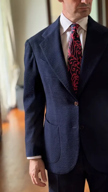 Detail of John Philip Green’s navy suit and red patterned tie.