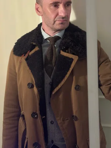 John Philip Green in a brown coat with a dark shearling collar.