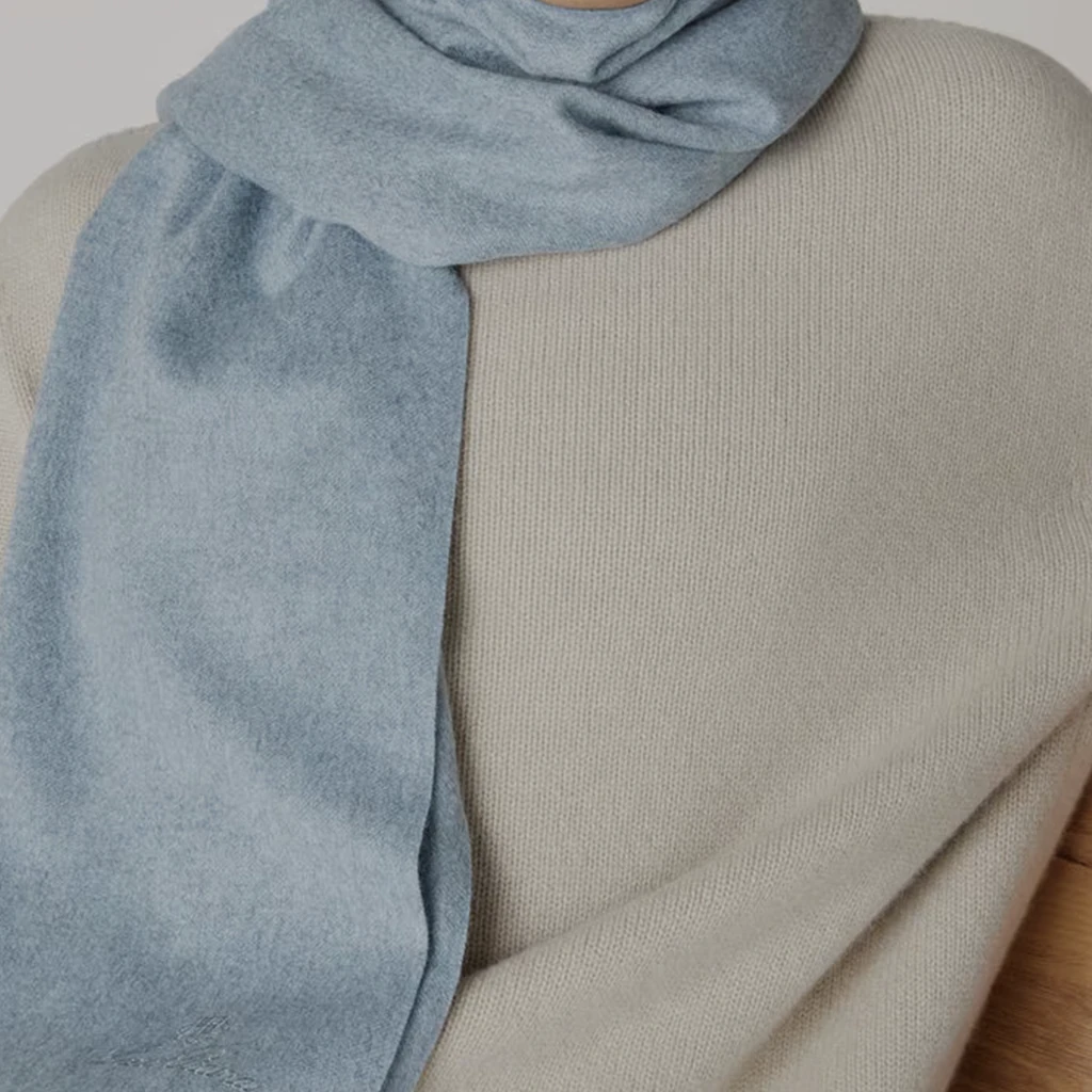A pale blue Loro Piana scarf draped over cream knitwear