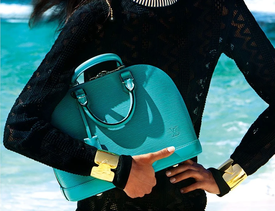 A turquoise Epi Alma in the 2015 Spirit of Travel campaign, held against black clothing and a blue sea